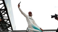 Begini salah satu cara Hamilton merayakan kemenangan di Silverstone. Ia melakukan swafoto alias selfie di atas sebuah pagar besi. (Foto: REUTERS/Andrew Boyers)