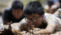 Salah satu peserta pun ada yang sampai merangkak di kubangan lumpur. Dalam event ini, tercatat ada sekitar 4.000 orang yang berpartisipasi (Aly Song/Reuters)