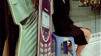 Dari foto yang diambil tahun 2000 ini, tampak seorang wanita asyik menggunakan ponsel di toko Nokia. Foto: Getty Images