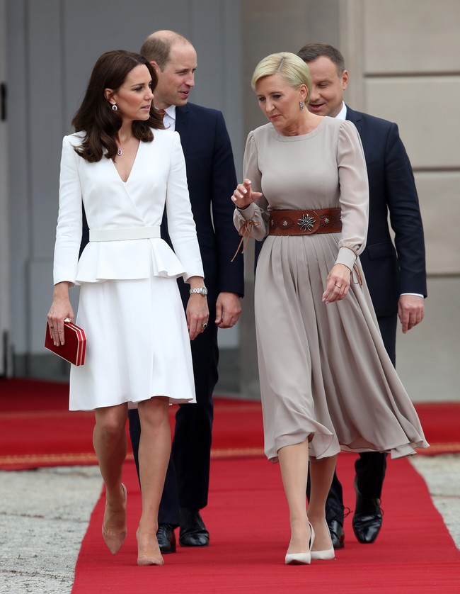 Tiba di Warsaw, Polandia, Kate Middleton mengenakan gaun peplum putih Alexander McQueen, clutch merah Jenny Packham dan sepatu pump dari Gianvito Rossi.