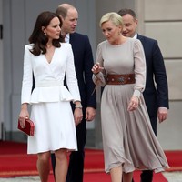 Tiba di Warsaw, Polandia, Kate Middleton mengenakan gaun peplum putih Alexander McQueen, clutch merah Jenny Packham dan sepatu pump dari Gianvito Rossi.