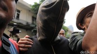 Ia tampak menutupi wajahnya dengan hoodie bermotif army itu.