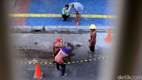 Pekerja membongkar jalan yang akan digali.