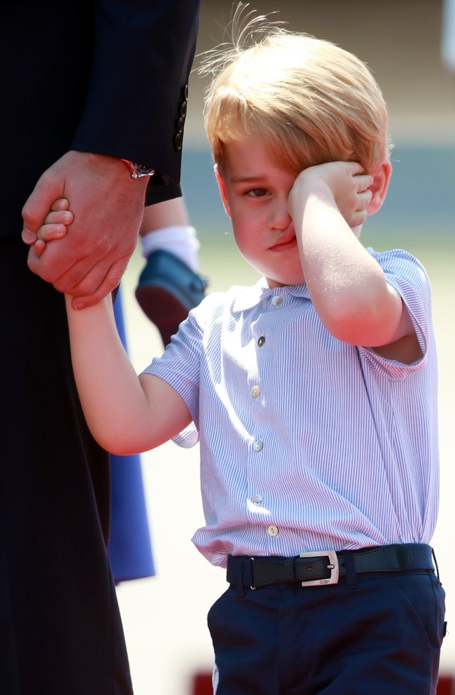 Pangeran George tampak mengantuk saat tiba di Jerman. Ia berkali-kali mengusap mata dan wajahnya, juga bersandar ke lengannya ketika turun pesawat. Foto: Getty Images
