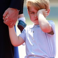 Pangeran George tampak mengantuk saat tiba di Jerman. Ia berkali-kali mengusap mata dan wajahnya, juga bersandar ke lengannya ketika turun pesawat. Foto: Getty Images