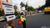 Polisi membawa poster untuk memberi petunjuk pada pengendara yang akan menuju Jl. Pramuka agar melewati flyover.