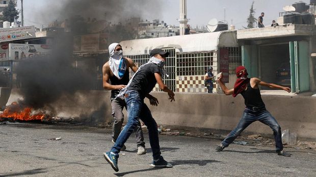 Warga Palestina melemparkan batu ke arah pasukan keamanan Israel di Tepi Barat