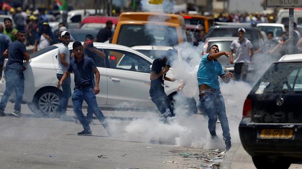 Warga Palestina melemparkan balik gas air mata ke arah pasukan keamanan Israel di Tepi Barat