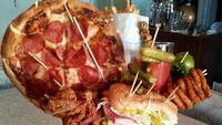 Bayangkan minuman diberi tumpukan makanan berukuran besar. Ada acar, burger, ayam goreng hingga pizza. Gimana cara makannya ya? (Foto: Istimewa)