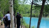 Wisatawan beragam usia terlihat asyik berswafoto berbekal kamera digital sambil memilih titik berpose dengan latar belakang Blue Pond (Baban/detikTravel)