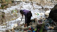 Seorang warga mengumpulkan botol-botol plastik yang tersangkut di pinggir sungai.
