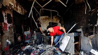 Seorang pria juga terlihat mengumpulkan barang-barang di toko miliknya yang hangus terbakar karena bom bunuh diri.