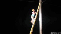 Seorang petugas memanjat tiang listrik untuk mengecek trafo PLN.