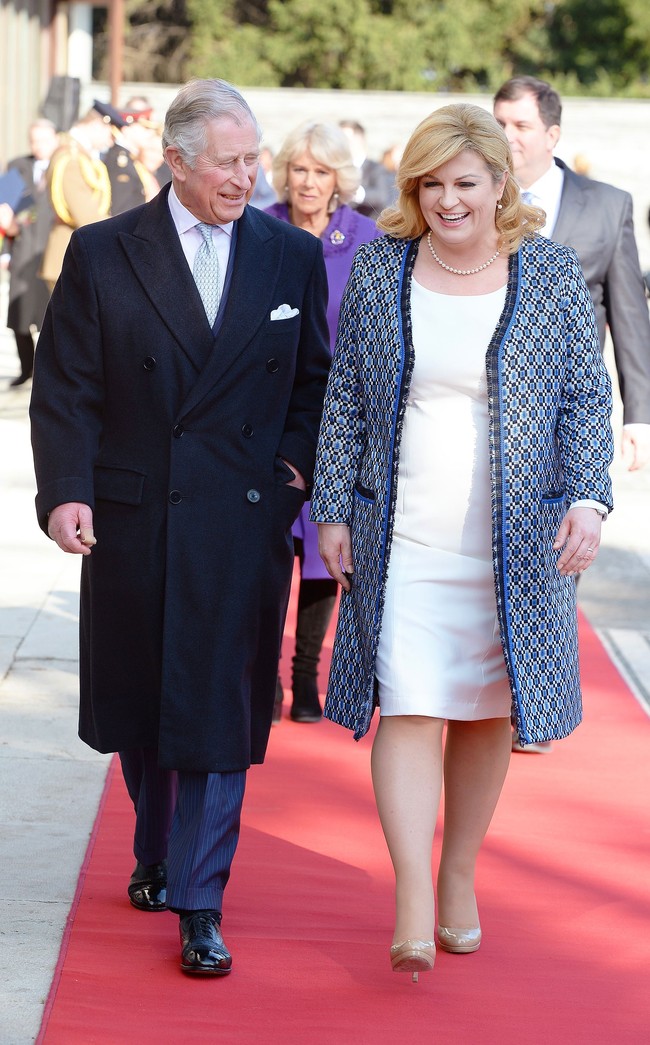 Untuk menyambut Pangeran Charles dan istrinya Camilla, Kolinda Grabar-Kitavoric memilih padanan gaun pas badan warna putih yang dipadukan mantel bermotif geometris. Gaya yang elegan sekaligus anggun. Foto: Getty Images