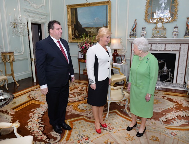 Berkunjung ke istana Buckingham dan bertemu Ratu Elizabeth II, Kolinda tampil dalam balutan setelan blazer dan rok pensil. Blazer hitam-putih menampilkan ilusi tubuh Presiden Kroasia yang lebih ramping. Foto: Getty Images