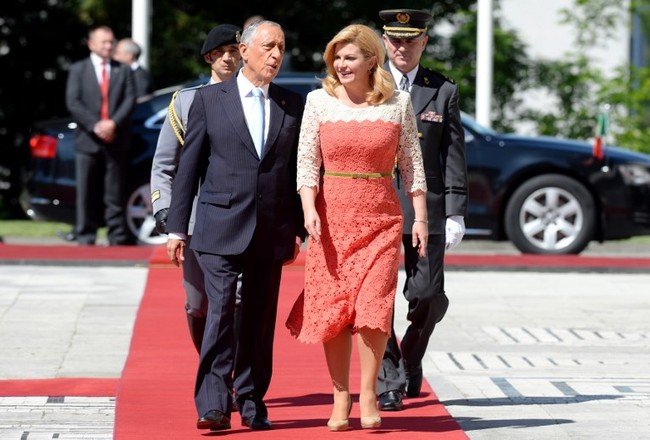 Kolinda tampil feminin berbalut gaun midi dengan sentuhan lace atau brokat warna coral-putih saat menyambut Presiden Portugal Marcelo Rebelo de Sousa di Zagreb, Kroasia, 18 Mei 2017. Foto: AFP