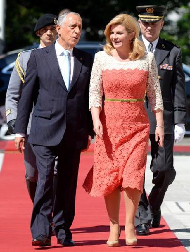 Kolinda Grabar-Kitavoric tampil feminin berbalut gaun midi dengan sentuhan lace atau brokat warna coral-putih saat menyambut Presiden Portugal Marcelo Rebelo de Sousa di Zagreb, Kroasia, 18 Mei 2017. Foto: AFP