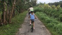 Gary juga terlihat menikmati waktu liburannya dengan bersepeda di kawasan Ubud. Bersama putrinya dan juga staff hotel yang jadi pemandu jalan (Instagram/@gneville2)