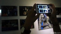 Seorang pengunjung mengabadikan kembali foto-foto yang dipamerkan.