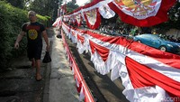 Seorang warga melintas di depan bendera dan umbul-umbul yang dijual di Jalan Ragunan.