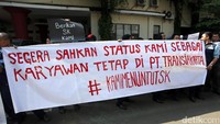 Karyawan TransJakarta membentangkan spanduk tuntutan.