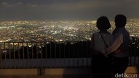 Pasangan dewasa dan muda saling bergandengan sambil mengabadikan momen romantis di puncak Moiwa berlatar hamparan indahnya ibu kota Hokkaido itu dengan menggunakan kamera (Baban/detikTravel)