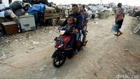 Pengendara sepeda motor melintas di sekitar tumpukan sampah di Taman BMW.