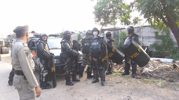 Personel polisi mengenakan tameng dan helm pengaman.