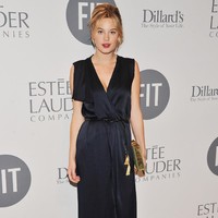 Model berdarah Prancis-Amerika ini tampil glamor dalam balutan wrap dress biru navy berbelahan dada rendah, dengan sabuk beraksen emas. (Foto: Getty Images)