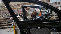 Seorang pekerja menyiapkan pintu mobil.