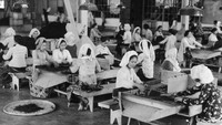 Sejumlah pekerja wanita tengah bekerja di sebuah pabrik teh dengan pakaian tradisional yang khas. Three Lions/Getty Images.