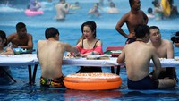 Di Chongqing, China, warga melakukan aktivitasnya di sebuah water park. Bahkan main mahjong pun dilakukan sambil berendam.(Foto: REUTERS/Stringer)