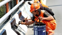 Petugas Penanganan Prasarana dan Sarana Umum (PPSU) mengecat ulang pembatas jalan di flyover Taman Ria Senayan.