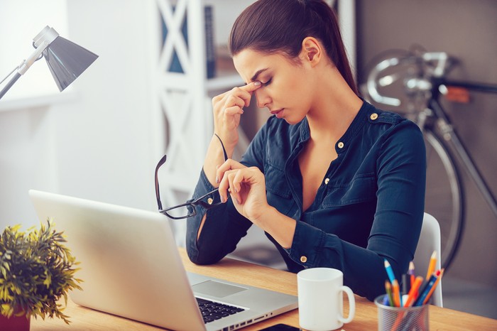Tanda-tanda gejala serangan jantung Frustrated young woman keeping eyes closed and massaging nose while sitting at her working place in office