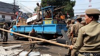 Petugas membongkar kios PKL yang berdiri di atas trotoar.
