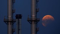Bulan yang terlihat saat gerhana sebagian. Bulan terlihat di belakang deretan cerobong asap di Delimara, Malta (Foto: REUTERS/Darrin Zammit Lupi)