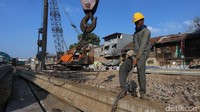 Pekerja mengikat tali baja pada beton yang akan digunakan untuk menurap Sungai Ciliwung.