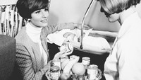 Ini foto seorang wanita yang sedang bepergian dengan bayinya. Pada tahun 1968, Scandinavian Airlaines memulai sebuah layanan makanan bayi yang ditaruh dalam wadah stoples untuk penumpang yang membawa anak. (Foto: Istimewa)
