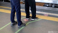 Dua orang penumpang menunggu KRL dengan berdiri di batas antrean.