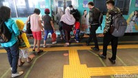 Para penumpang menaiki KRL melewati garis antrean.