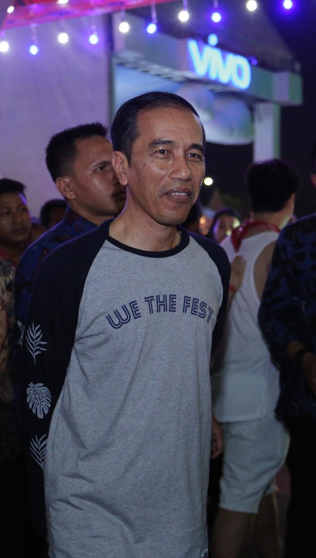 Jokowi datang ke JIEXPO Kemayoran, Jumat (11/8/2017) malam mengenakan kaus bertuliskan We The Fest. Kaus tersebut merupakan merchandise resmi dari festival musik yang berlangsung selama tiga hari itu. Foto: Hanif Hawari/detikHOT