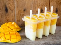 Yellow mango homemade popsicles on white wooden background with hazy vintage editing