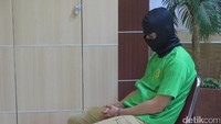 Rio mengenakan baju tahanan hijau dan penutup wajah. Foto: Desi Puspasari