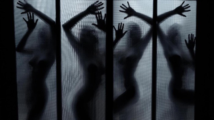 Young woman using mobile phone in dark room at night