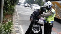 Pengendara sepeda motor diberi surat tilang.