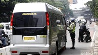 Polisi menghentikan minibus dan memeriksa surat-surat kendaraan.