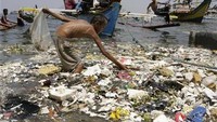 Seorang pria memungut sampah plastik di antara perahu di pinggiran pantai di Manila pada April 2008 (Foto: Reuters)