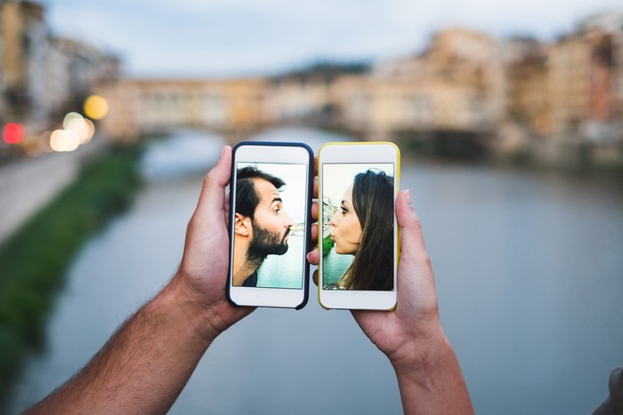 577957468 Young couple smart phone screen kiss. Florence Italy