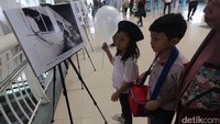 Anak-anak serius melihat foto yang dipamerkan.