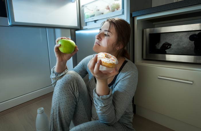 Teenage girls sitting in a bedroom eating popcorn